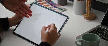 İki tasarımcının rahat çalışma alanlarındaki projelerine danışmanlık yaparken çekilen görüntüler beyaz masadaki model tablet, dizüstü bilgisayar ve tasarımcı malzemeleriyle