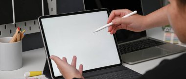 İki tasarımcının, projelerini rahat çalışma ortamında tartışırken çekilmiş görüntüleri beyaz masadaki tablet, dizüstü bilgisayar ve tasarımcı malzemeleriyle