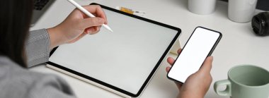 Kadın tasarımcının yatay model akıllı telefon hakkında bilgi ararken maket tabletle çalışırken çekilmiş görüntüsü 