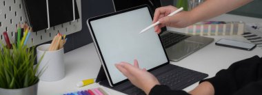 İş kadınının, partneriyle projesinde danışmanlık yaparken tablet üzerinde çalışırken çekilmiş bir fotoğrafı.
