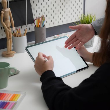 Moda işyerinde meslektaşına danışırken stilus kalemle tablet üzerinde çalışan kadın tasarımcının yakın görüntüsü