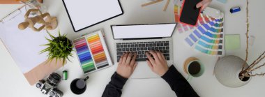 Model dijital cihazlar, tasarımcı gereçleri ve konforlu çalışma alanındaki dekorasyonlar üzerinde çalışan tasarımcıların üst görünümü 