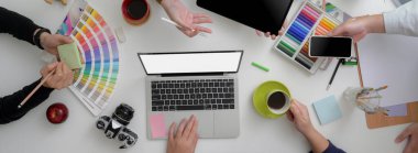 Tasarımcı takımı, en az toplantı odasındaki projeleri için beyaz masaya dizüstü bilgisayar, tablet, akıllı telefon ve tasarımcı malzemeleri ile danışmanlık yapıyor.   