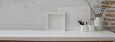 Çağdaş çalışma alanı görünümünü maket çerçeve, kırtasiye, dekorasyon ve tuğla duvarlı beyaz masa üzerindeki kopyalama alanı ile kapat 