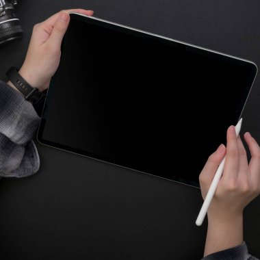 Dijital tablet üzerinde çalışan kadın serbest çalışanın karanlık modern çalışma alanında stilus kalemle çekimleri.
