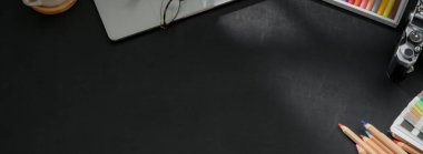 Boyama araçları, dizüstü bilgisayarlar, kamera ve siyah çalışma tablosu üzerine kopyalama alanı ile tasarımcı çalışma alanının genel görüntüsü  