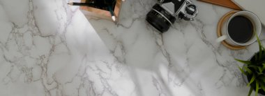 Kamera, kırtasiye malzemesi, kahve fincanı ve mermer masadaki fotokopi alanı ile modern fotoğrafçının üst görünümü  