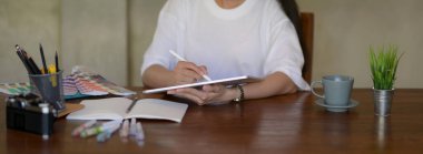 Projesini kırtasiye malzemesi ve tasarımcı malzemeleriyle dijital tabletle çizerken kız üniversite öğrencilerinin görüntüsünü kapat