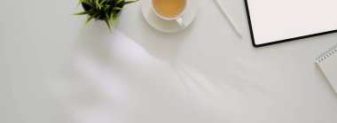 Tablet, malzeme, çay fincanı ve beyaz çalışma tablosu üzerindeki kopyalama alanı ile çalışabilecek minimal tasarımcının genel görüntüsü