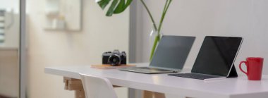 Bilgisayarlı, dijital tabletli, fincanlı, kameralı, ofis malzemeli ve cam bölmeli ofis dekorasyonlu rahat ofis masası.