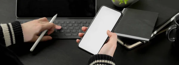 モックアップスマートフォンの情報を見ながらデジタルタブレットを操作するビジネスマンの作物のショット — ストック写真