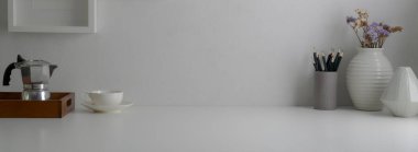 Kahve fincanı, kırtasiye malzemesi ve beyaz masa üzerinde beyaz duvarlı kopyalama alanı olan en küçük çalışma alanını kapat  