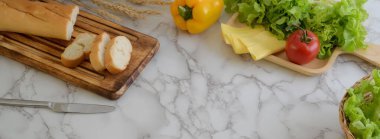 Fransız ekmeği, peynir, sebze ve ahşap tepside kesilmiş mermer mutfak masası ve kopyalama alanı.  