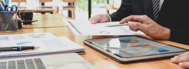 İş ortağının dijital tablet ve kağıt işlerindeki iş grafiğini analiz ederken yan görünümü 
