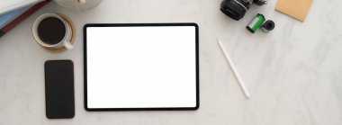 Mermer masasında tablet, akıllı telefon, kamera ve diğer malzemelerle en az fotoğrafçı olan işyeri manzarası 