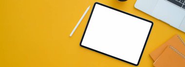 Boş ekran tableti, stili, dizüstü bilgisayarı ve sarı masadaki boşluğu kopyalayan yaratıcı çalışma alanının üst görünümü 