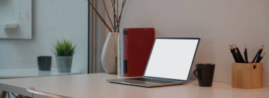 Ofis masasının maket dizüstü bilgisayarı, kitapları ve süslemeleri beyaz masanın üzerinde. 