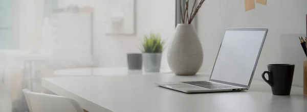 Boş dizüstü bilgisayarı, dekorasyonları ve beyaz masadaki alanı kopyalayan minimal ofis masasının yan görüntüsü  