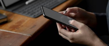 Kafedeki taşınabilir atölyede otururken akıllı telefon kullanan serbest çalışan kadın görüntüsü.
