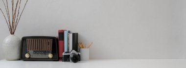 Vazo, klasik radyo, kitaplar, kamera, kırtasiye malzemesi ve kopyalama alanı ile çağdaş ev iç tasarımı görünümünü kapat