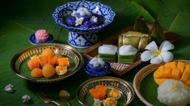 Porselen, ahşap tepsi ve pirinç çatal bıçak ve muz yapraklarıyla süslenmiş çiçeklerle servis edilen Tayland geleneksel tatlılarına yakından bakın.