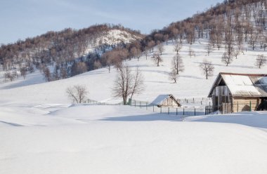 Köyde kış karlı bir dağın arka planında.