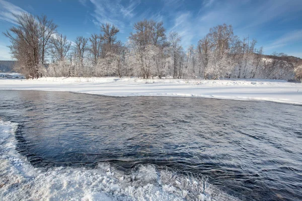 一条半冻的冬季河流 背景上有高山 村庄和白霜中的树木 — 图库照片