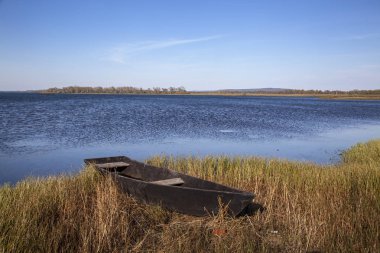 Göldeki köy tekneleri. Aktif gökyüzü, suda dalgalanmalar. Metin için boş alan var.