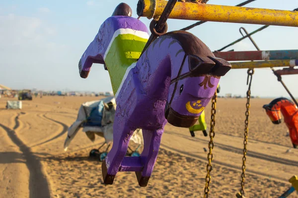 Körhinta fából készült lovakkal a tengerparton a gyerekek szórakozására. Merry megy körbe részeként szórakoztató tevékenységek Marina Beach, Chennai, India. — Stock Fotó