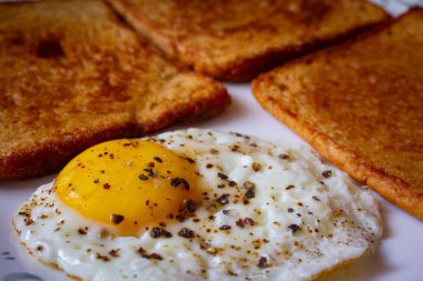 Tereyağlı buğday ekmeği ve yumurtanın gözü. Yumurtalı ekmek ve kızarmış ekmek..