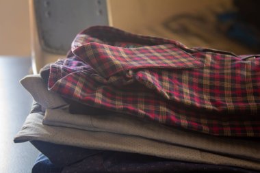 Arka planda demir kutuyla ütülendikten sonra üst üste dizilmiş katlanmış gömleklerin görüntüsü.