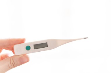 Beyaz arka planda skorbord üzerinde boş bir alan olan elektronik termometreyi tutan bir kadının parmakları.