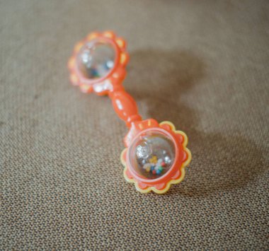 Bebek kırmızı çıngırak kumaşın üzerinde yatıyor