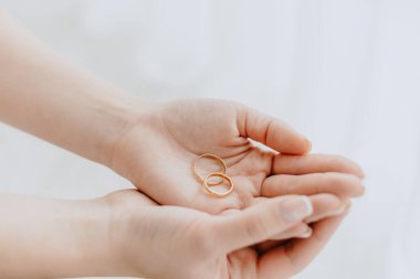 Gelinin elleri, gelinle damadın alyanslarını hafif arka planda tutar.