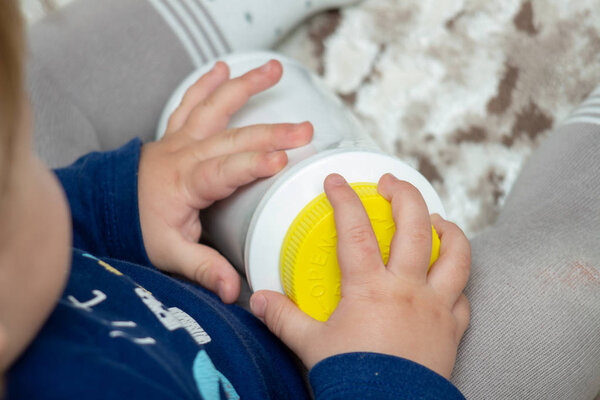 A child independently tries to open a plastic bottle of medicine