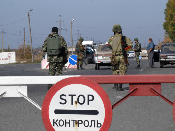 SELIDOVO, UKRAINE - OCTOBER, 2014: Armed krainian border guards checks vehicles on  the security checkpoint