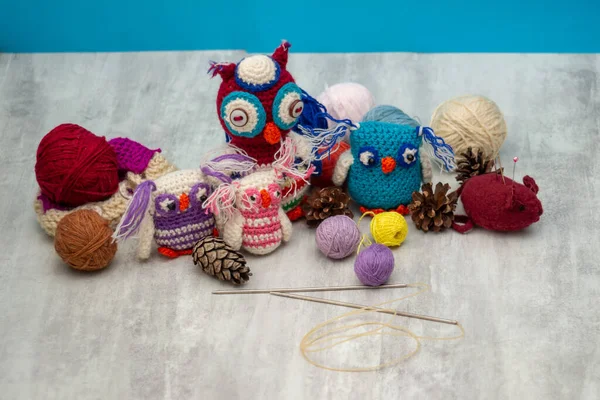 手作りの多色のニットおもちゃのフクロウ 糸のある皮 編み物針 テーブルの上のピン 針仕事と子供の創造性の概念 女性の趣味とお祝いの装飾 青の背景 — ストック写真