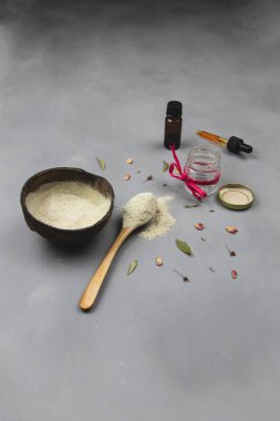 Yüzünde bentonit kil, temel yağlar, bitkiler ve aromaterapi bulunan yüz maskesi gevşeme ve yüz temizleme için gri arka planda.