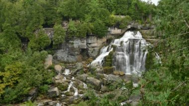 Kayaların üzerinde çağlayan şelaleyi çevreleyen lüks bitki örtüsünün geniş görüşü