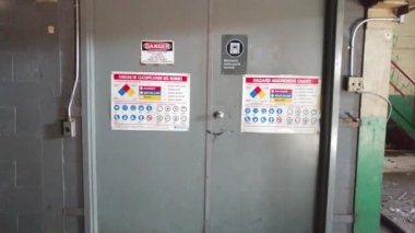 Eski elektrikli kapılardaki iki dilli güvenlik işaretine doğru hareket eden kamera.
