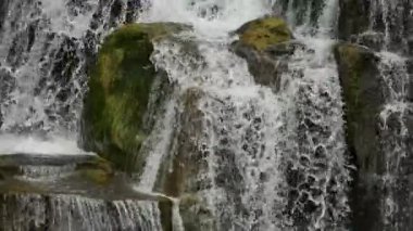 Büyük taşlı şelalelerin ve farklı seviyelerde akan suyun yakınına.