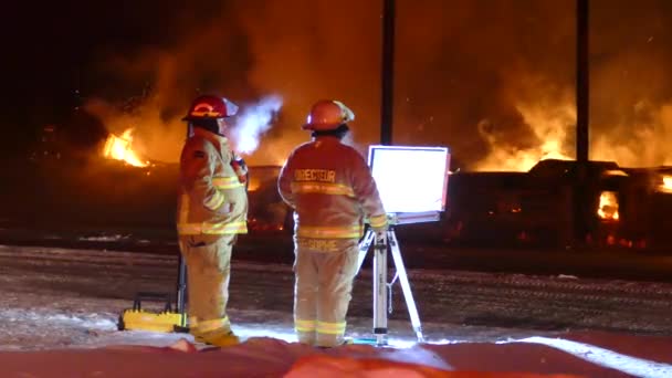 Dvojice hasičů stojící na velitelském stanovišti s plameny hořícími v pozadí