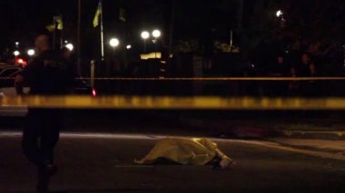 Bir sokakta muşambayla kaplanmış bir ceset.