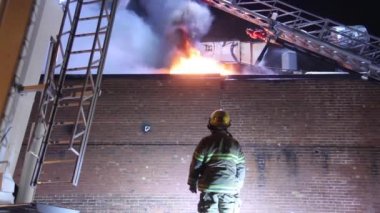 İtfaiyeci bir binanın yanmasını izliyor.