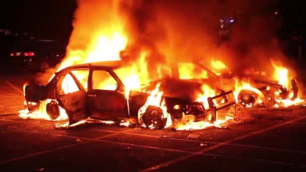 两辆夜间燃烧的汽车 后面有暴徒和打人的军官 — 图库视频影像