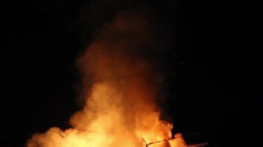 Parlayan turuncu duman bulutu ve gece gökyüzünde yükselen parıltılar