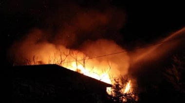 Belirsiz yapının üzerinde gece gökyüzünde şiddetle yükselen alevler ve ateş.