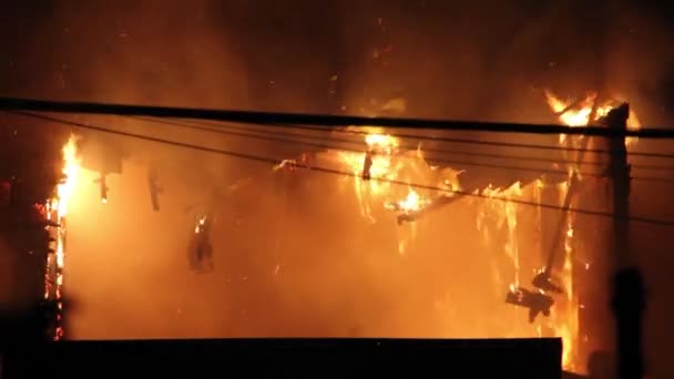 夜間に激しく燃焼する構造物の前に見られる送電線 — ストック動画
