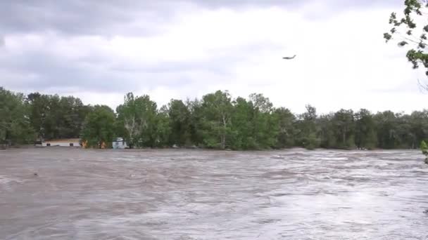军机在洪水泛滥的河流上飞行 载满了拖车和瓦砾 — 图库视频影像