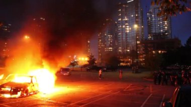 Arkasında yüksek konut binaları bulunan arabalar kargaşa içinde şehirde yanıyor.